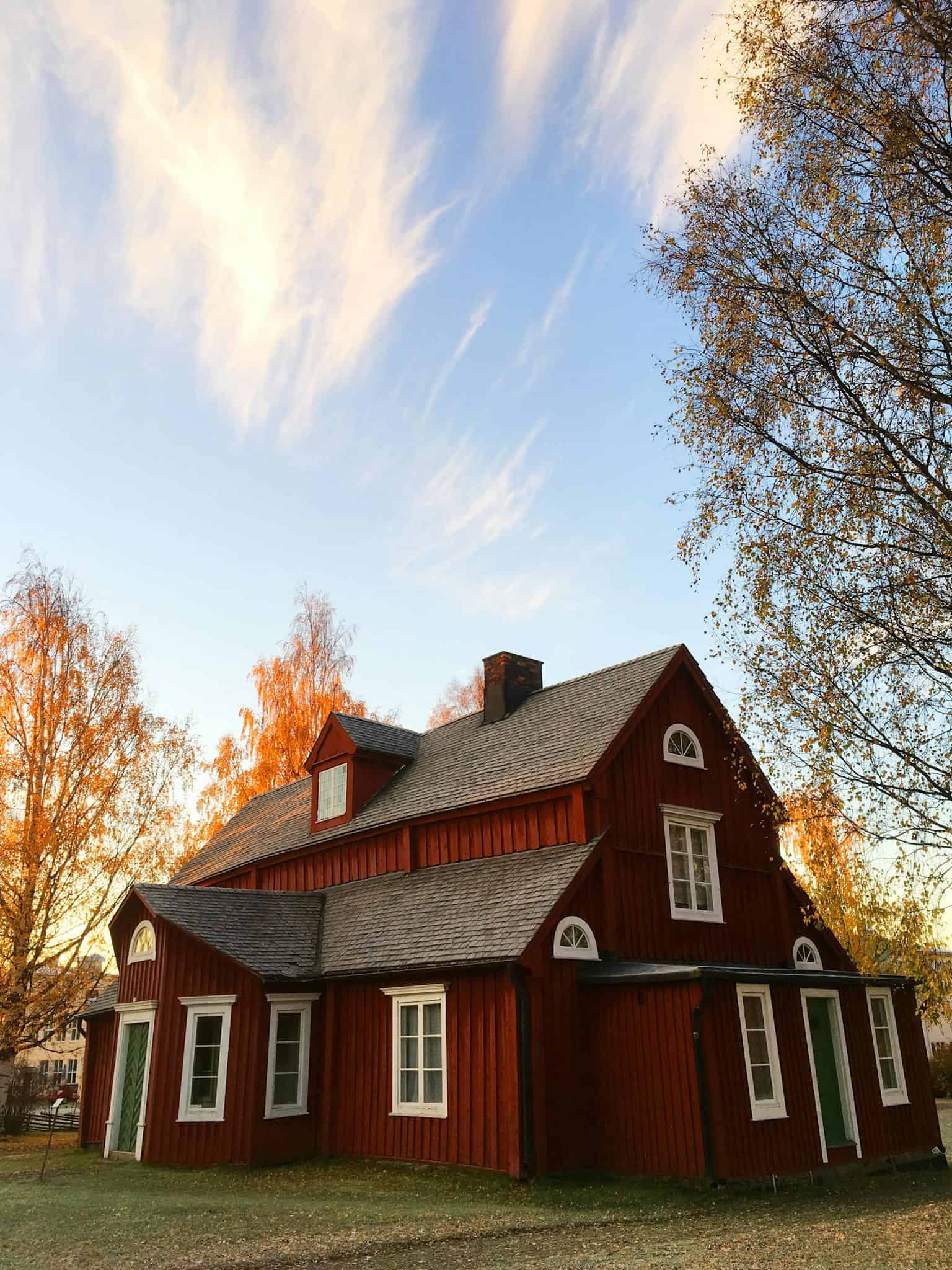 Traditional red wooden house with autumn trees.